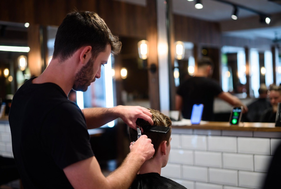 Kapper knipt het haar van een klant met schaar en kam in een kapsalon